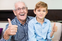 Happy senior man and grandson showing thumb up